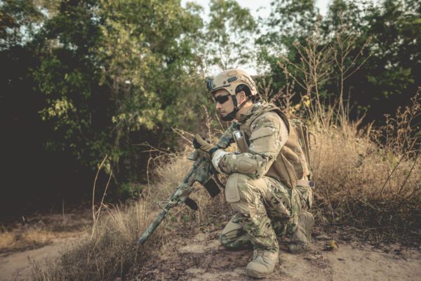 A soldier sitting in the forest with gun in his hand